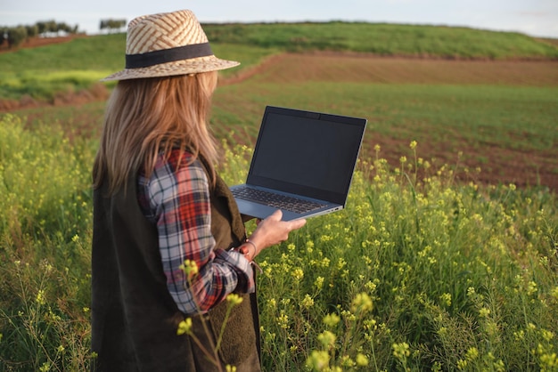 Vrouwelijke veldingenieur met een laptop die landbouwplantages onderzoekt Integratie van vrouwen