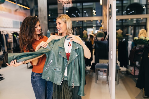 Vrouwelijke verkoper helpt koper om te kiezen tussen verschillende kleding.