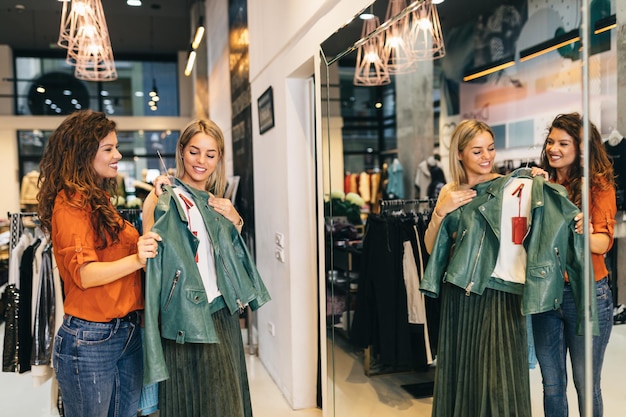 Vrouwelijke verkoper helpt koper om te kiezen tussen verschillende kleding.