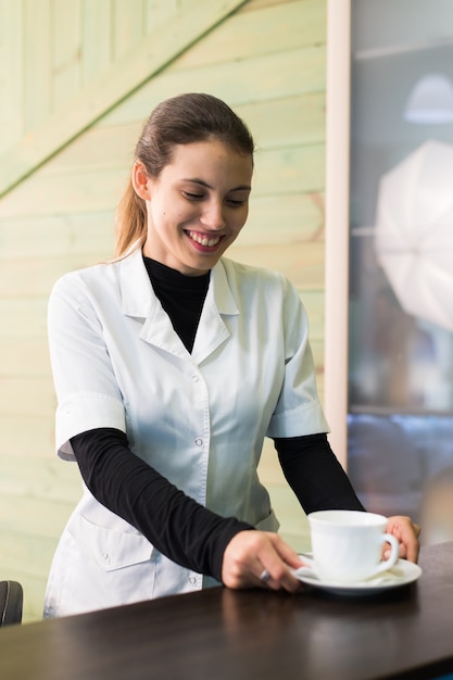 Vrouwelijke verpleegster bij een bureau dat koffie maakt