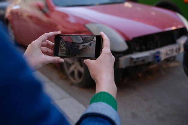 Vrouwelijke verzekeringsmakelaar die foto's maakt van auto na ongeval op moderne smartphone