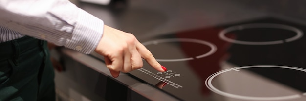 Vrouwelijke vinger drukt op knop op aanraking elektrisch fornuis verkoop van huishoudelijke apparaten koncetp