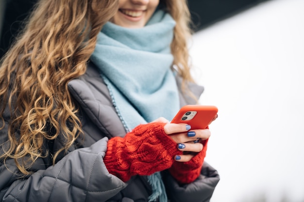 Vrouwelijke vingers die buitenshuis op mobiel tikken.