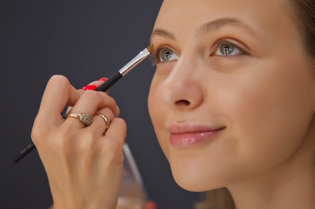 Vrouwelijke visagist maakt leuke mooie jonge vrouw in de schoonheidssalon.