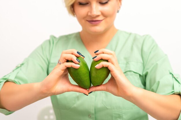 Vrouwelijke voedingsdeskundige arts met biologisch avocadofruit. Gezond levensstijlconcept.