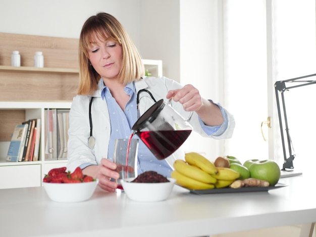 Vrouwelijke voedingsdeskundige die hibiscus-infusiedrank schenkt