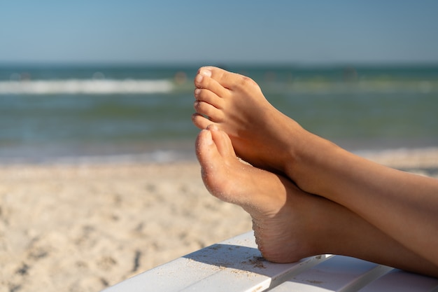 Vrouwelijke voet met halluxvalgus op het strand op de dag van de vakantiezomer