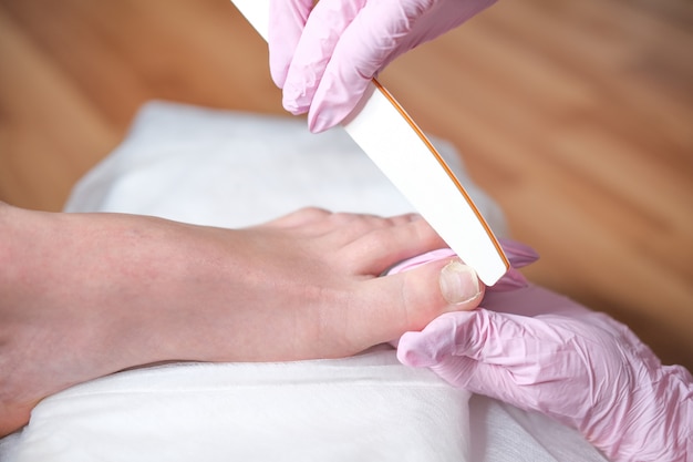Vrouwelijke voet tijdens pedicureprocedure in een schoonheidssalonclose-up. Podotherapeut. Behandeling van voeten en nagels