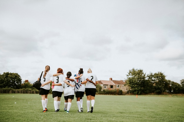 Vrouwelijke voetbalspelers die samen kruipen en lopen