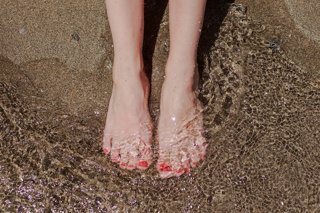 Vrouwelijke voeten in het zand op zee