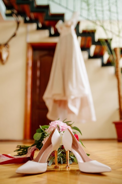 Vrouwelijke voeten in witte huwelijkssandalen met een boeket camomiles
