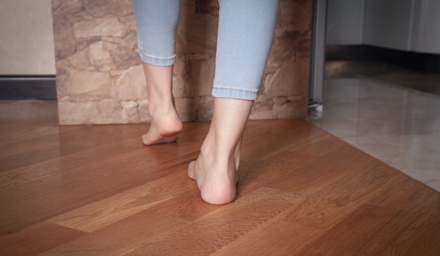Vrouwelijke voeten lopen op de vloer thuis.