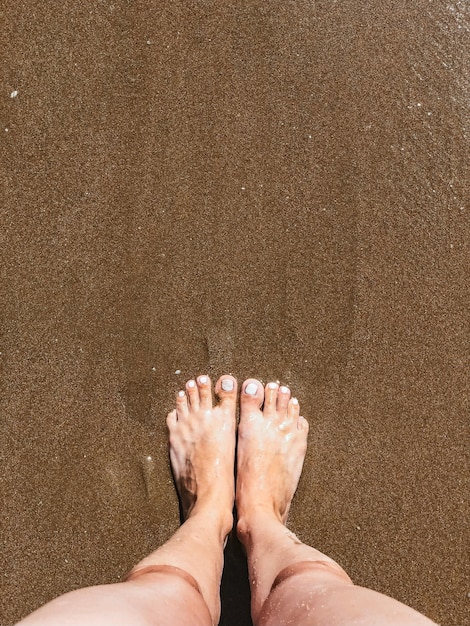 Vrouwelijke voeten staan op het zand bovenaanzicht