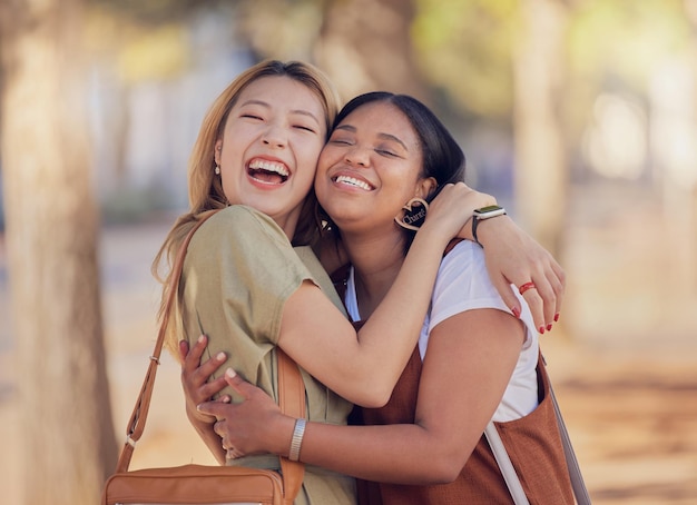 Vrouwelijke vrienden en gelukkige knuffel in de buitenzon met omhelzing, liefde en glimlach in de zomer voor vakantie Diversiteit Aziatische vrouw en zwarte vrouw met geluk in natuurpark en samen in Jakarta