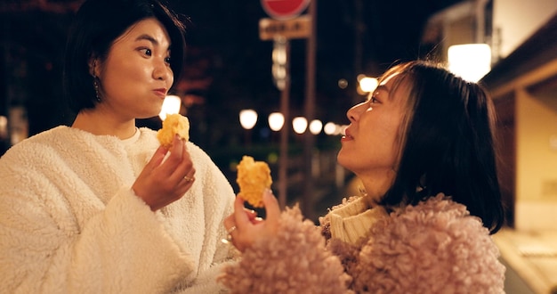 Vrouwelijke vrienden en straatvoedsel of het eten van Japanse snacks voor reis ervaring hongerig of lokale reis Vrouwelijke mensen stoep en nacht wandelen op vakantie voor voeding cultuur avontuur of traditionele