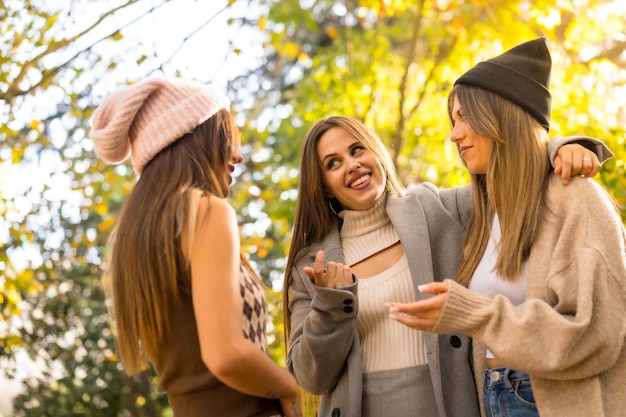 Vrouwelijke vrienden praten in een park in de herfst bij zonsondergang lifestyle en herfstoutfit