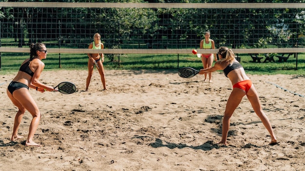 Foto vrouwelijke vrienden spelen strandtennis.