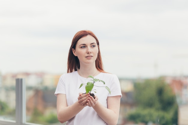 Vrouwelijke vrijwilliger houdt een zaailing van een bloemenboom in haar handen