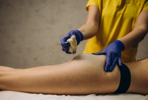 Vrouwelijke wax- of sugaring-master brengt warme wax aan met een spatel