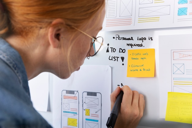 Foto vrouwelijke webdesigner met papieren en notities op kantoor
