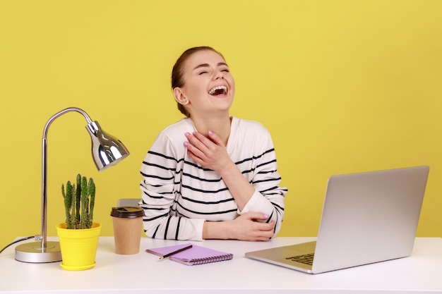 Vrouwelijke werknemer die hardop lacht omdat ze hysterisch is om een gekke grap op een laptop die pauze heeft op de werkplek