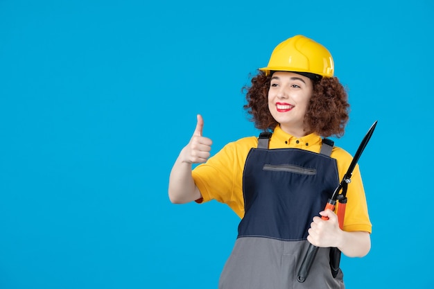 Vrouwelijke werknemer in uniform met snoeischaar op blauw