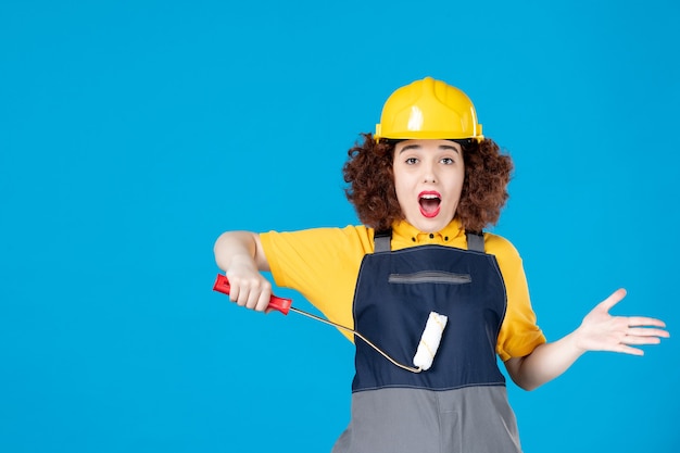 Vrouwelijke werknemer in uniform met verfroller op een blauw