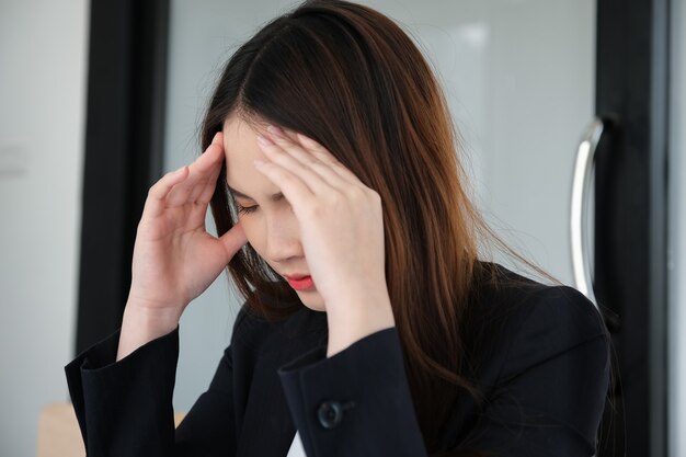 Vrouwelijke werknemers vertonen hoofdpijn door werk of teleurstelling door werk.