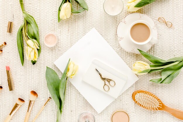Vrouwelijke werkruimte met gele tulp bloemen damesmode gouden accessoires dagboek bril op wit