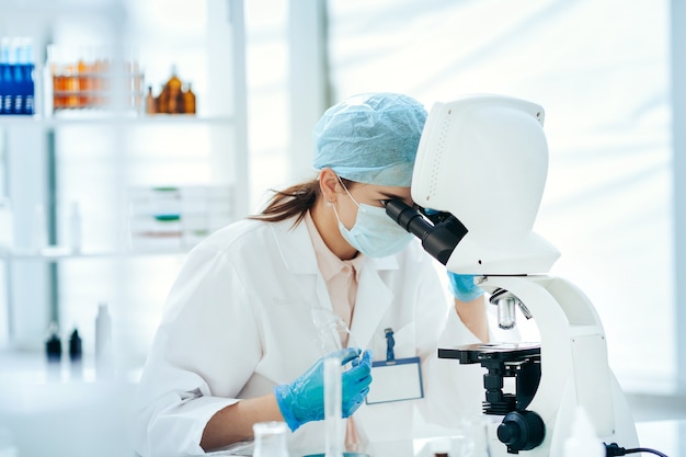 vrouwelijke wetenschapper die door een microscoop kijkt