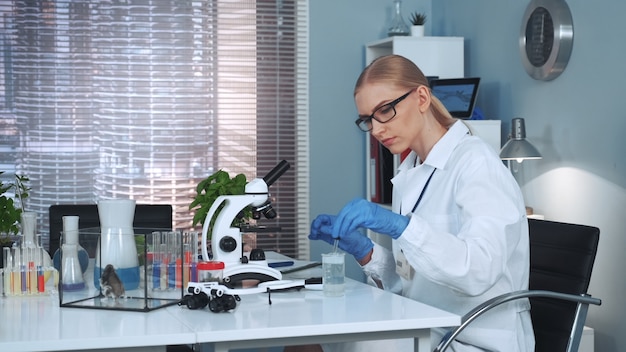 Vrouwelijke wetenschapper die experimenten met organische materialen in chemielaboratorium maakt