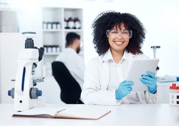Vrouwelijke wetenschapper en gelukkig in het lab met tablet op portret voor online medische onderzoeksinformatie en -kennis Vrouwelijke werknemer stagiaire en glimlach of trots op carrièregroei en kansen