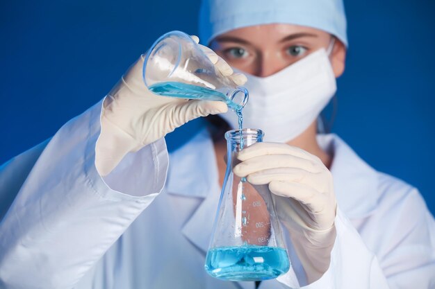 Vrouwelijke wetenschapper gieten reagens in kolf met monster op kleur achtergrond Laboratoriumanalyse