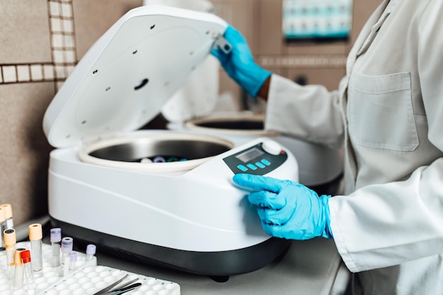 Vrouwelijke wetenschapper of technicus met beschermende handschoenen die in een modern laboratorium werken.