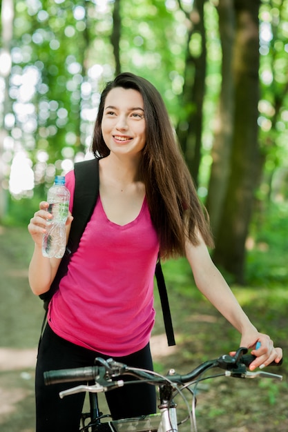 Vrouwelijke wielrenner op een fiets, met fles water, drank, sportvrouwen in het bos