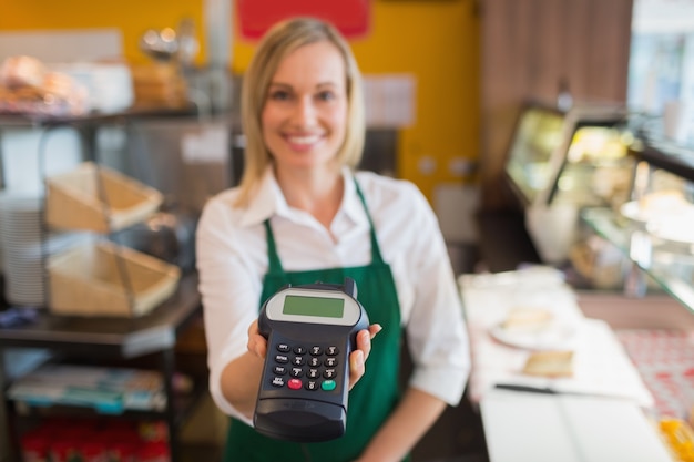 Vrouwelijke winkeleigenaar die creditcardlezer houdt