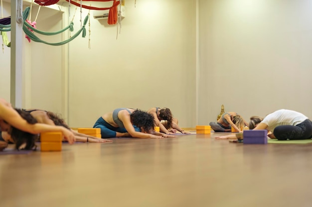 Vrouwelijke yogastudenten die balasana-houding leren