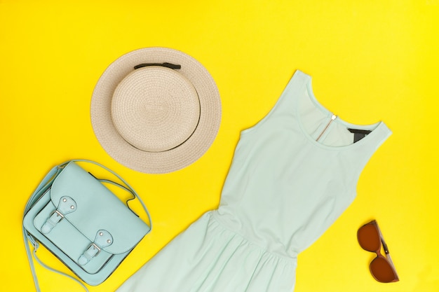 Foto vrouwelijke zomer kledingkast mint jurk, hoed, hahdbag, bril gele achtergrond