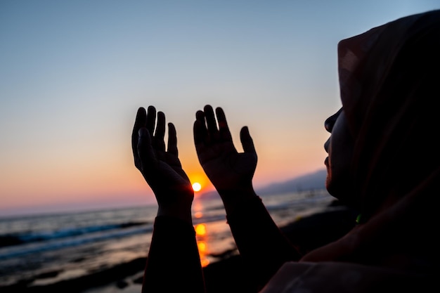 Foto vrouwen bidden tot allah op het strand bij zonsondergang