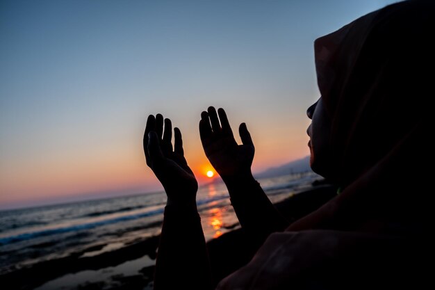 Vrouwen bidden tot allah op het strand bij zonsondergang