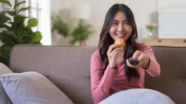 Vrouwen die brood eten terwijl ze tv kijken en van kanaal wisselen met afstandsbediening in levensstijl thuis
