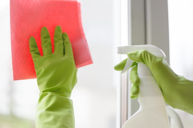 Vrouwen die een venster met nevel en doek schoonmaken. Detailopname