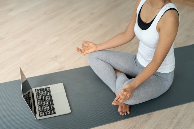 Vrouwen die een yoga-zithouding dragen, kalm ontspannen in huis