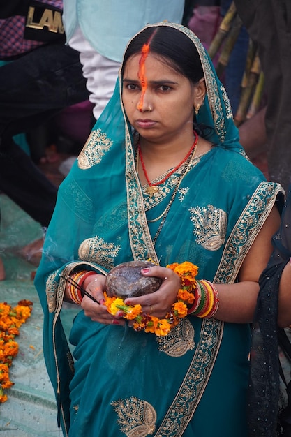 Vrouwen die het Chhath-festival uitvoeren, staan in rivierwater en offeren prasad