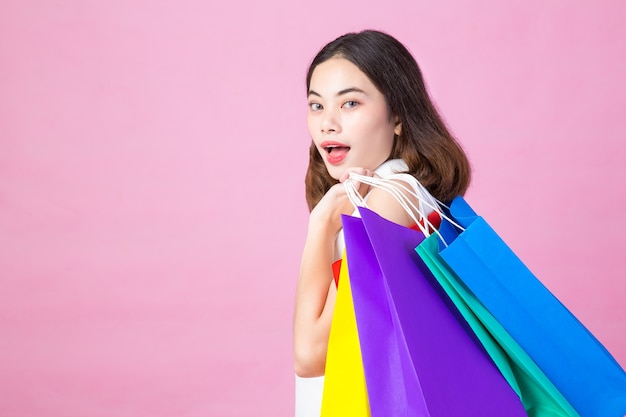 Vrouwen die het winkelen zakken houden die omhoog aan de kant op roze achtergrond op exemplaarruimte kijken