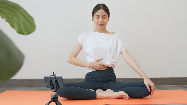 Vrouwen die sportkleding dragen die online cursus yoga op smartphone trainen