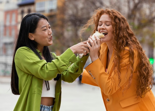 Vrouwen die straatvoedsel buiten eten