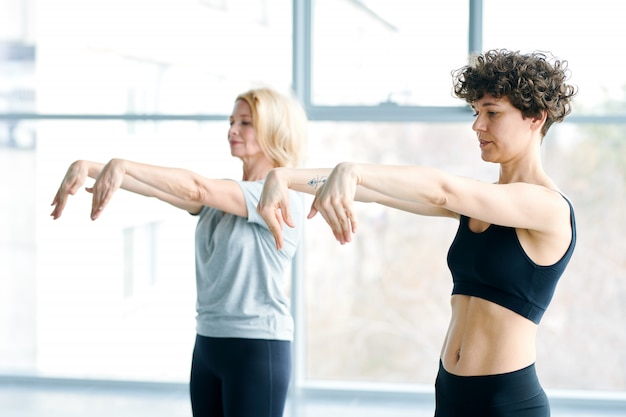 Vrouwen doen yoga naast een groot raam