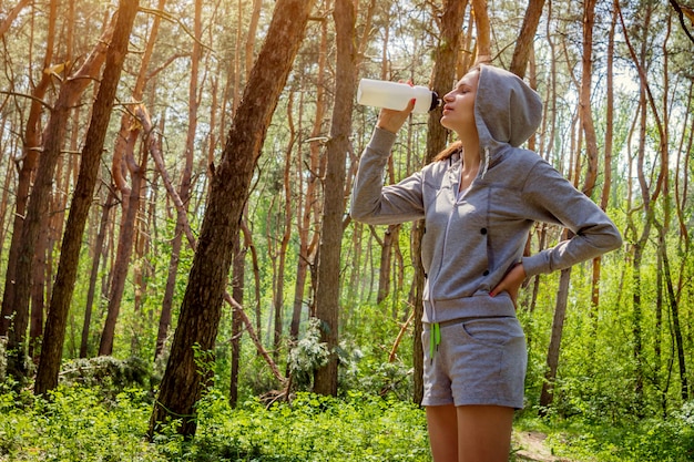 Vrouwen drinkwater na het lopen in het bos