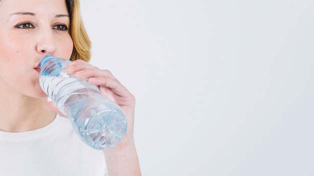 Vrouwen drinkwater van fles op wit